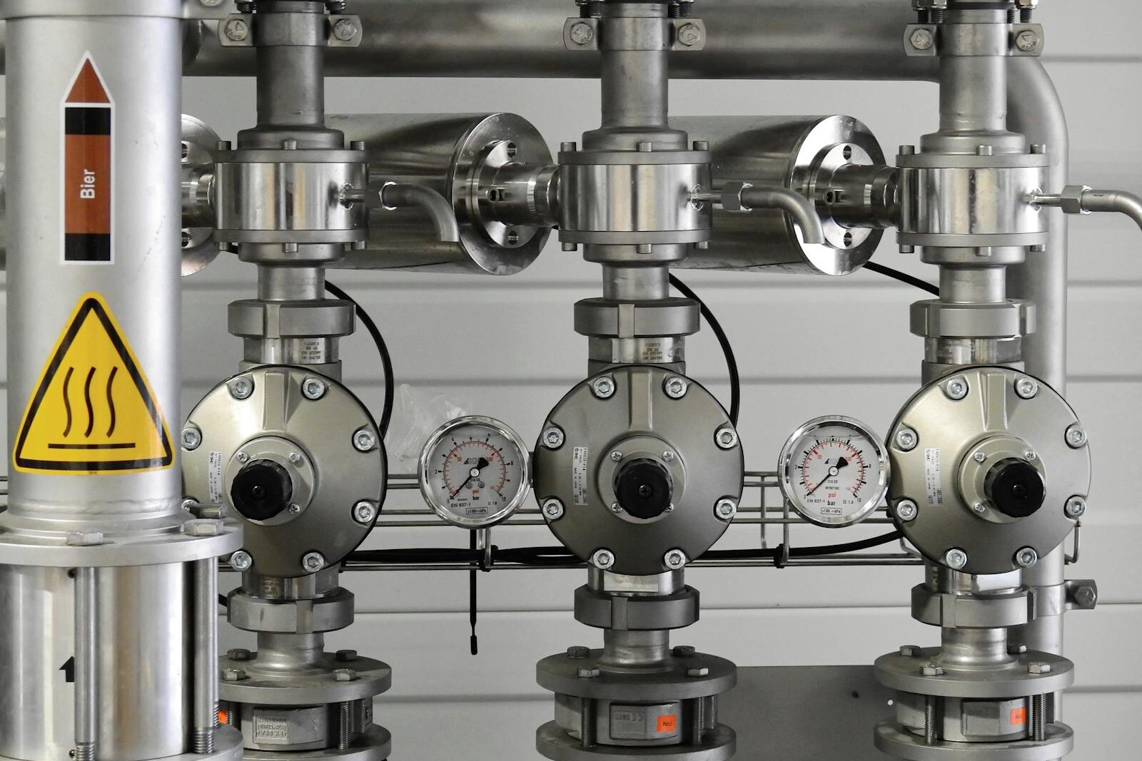 Close-up of stainless steel pipes with pressure gauges in an industrial setting.